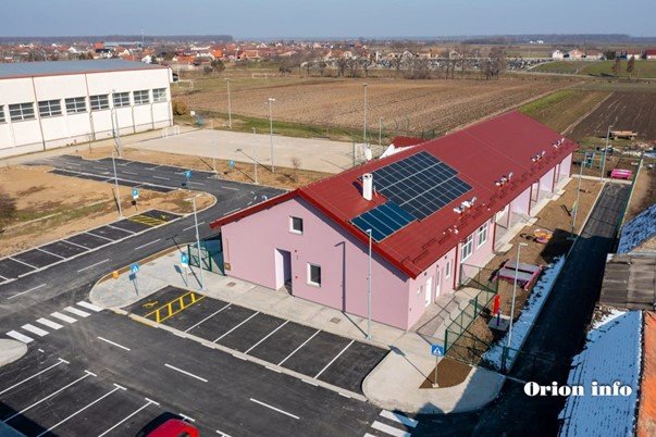 Zgrada s crvenim krovom i solarnim panelima.